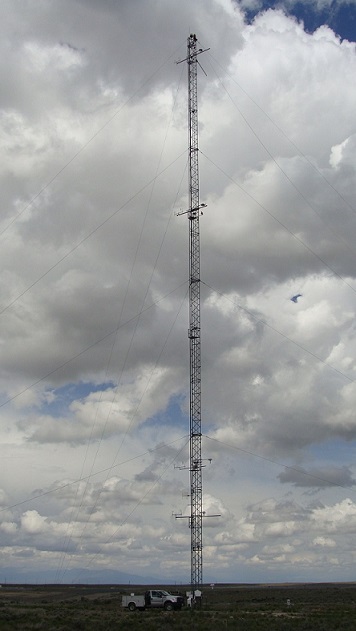 Tall metal tower with wires and sensors, with truck parked at the base for size comparison