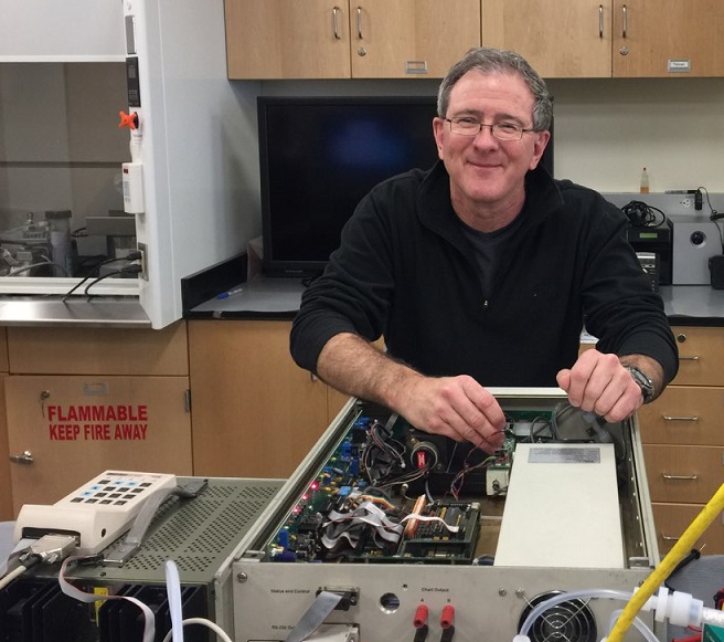 Dr. Luke with his hands inside an open metal box with lots of wiring