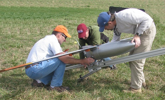 Three people attaching the sUAS to its catapult.