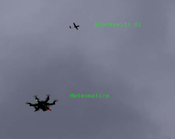  Two small unmanned systems in the sky above: one that looks like a small airplane and one six-rotor copter. width=