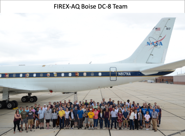 Large group of people standing under a plane with the NASA logo on the tail.