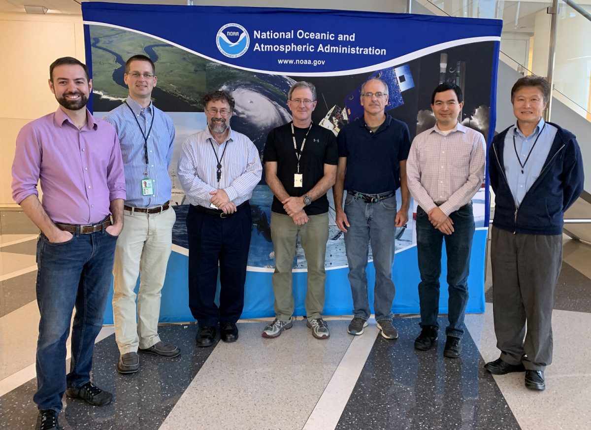 The seven recipients standing in a semi-circle in front of a display with the NOAA logo and program photos.