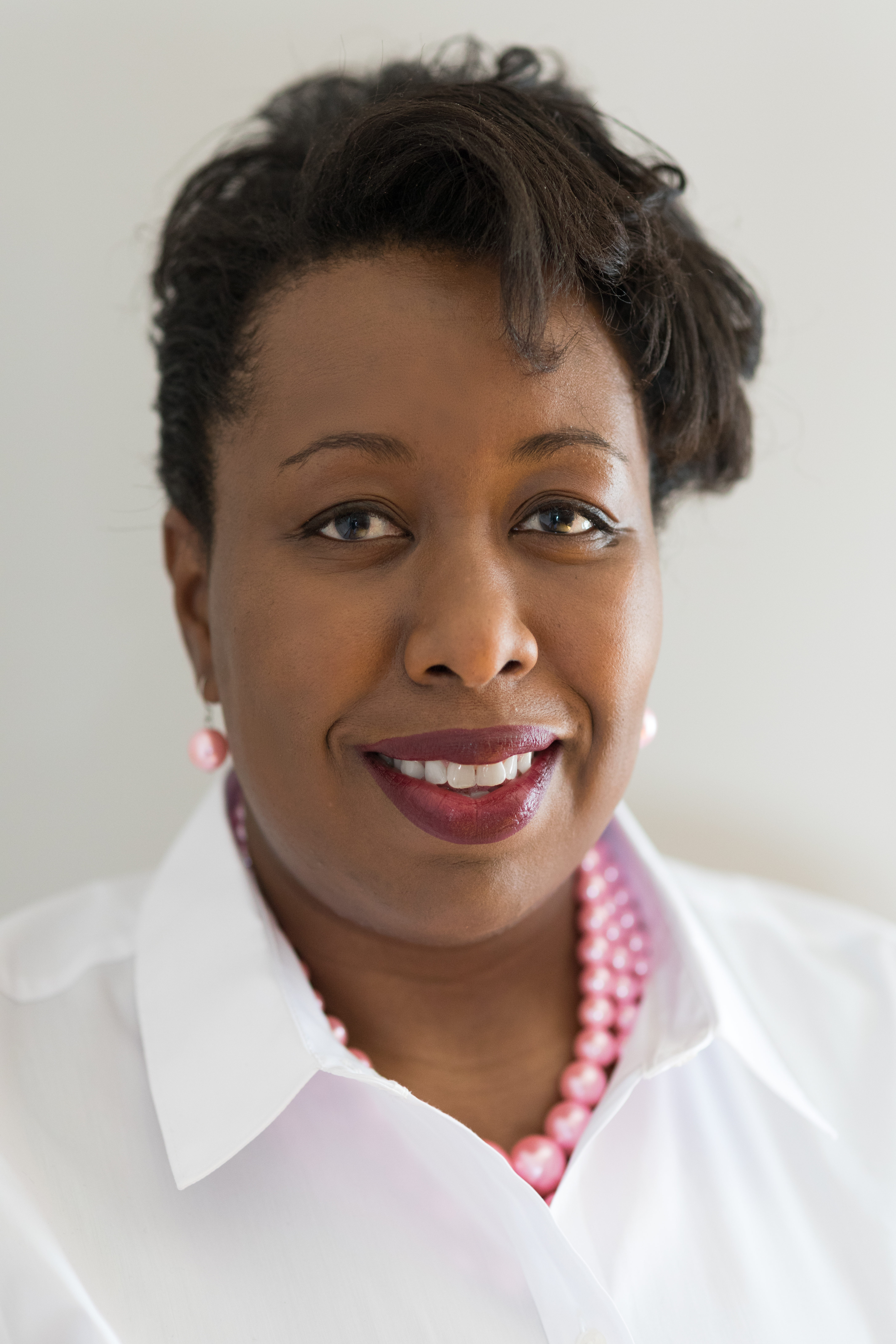 Dr Latoya Myles, portrait of a black woman in white shirt.