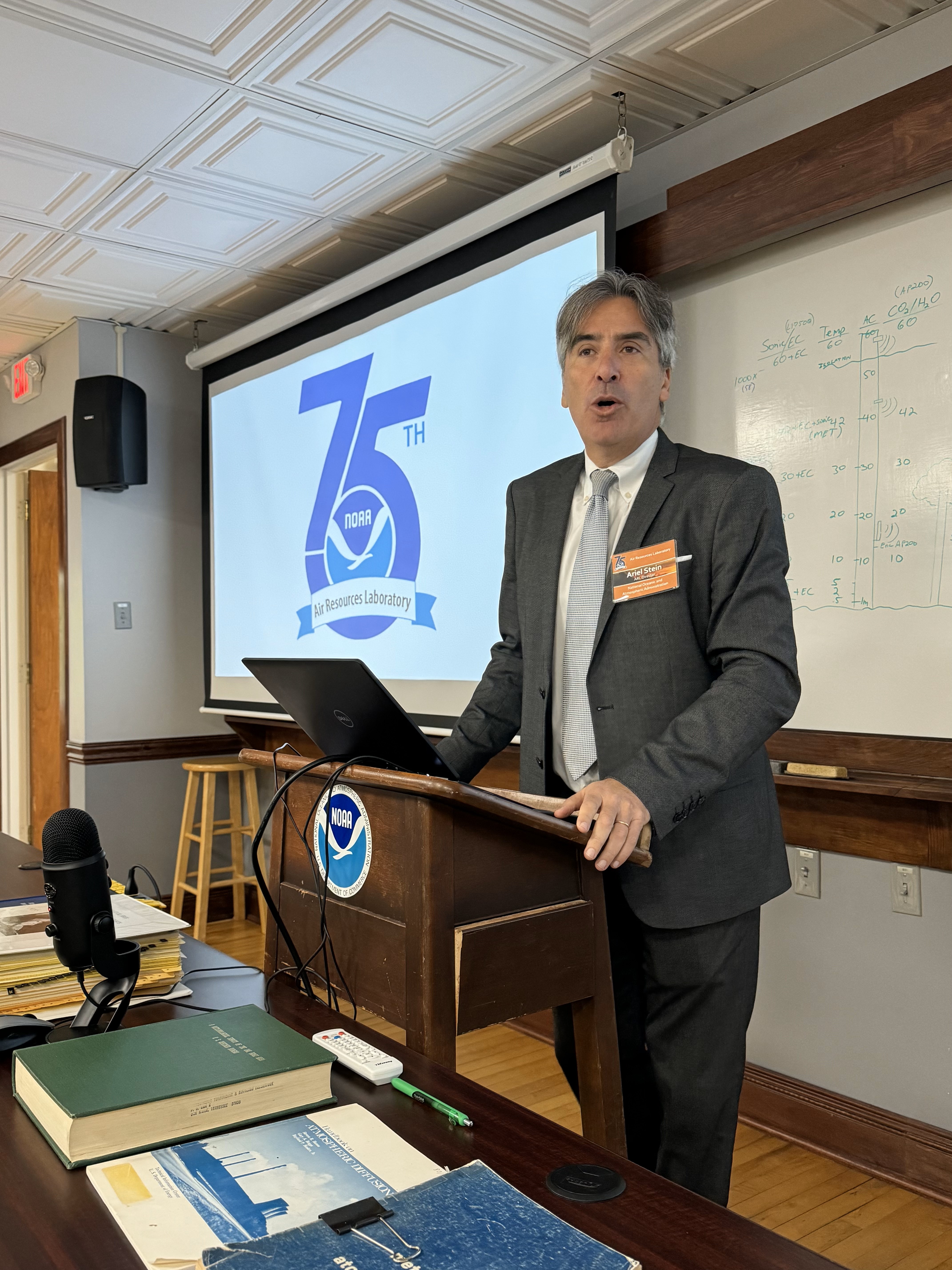 Man speaking at a podium in front of a screen