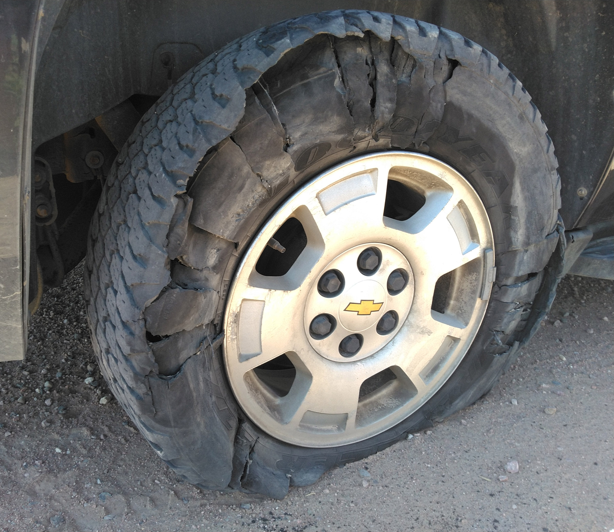 close up photo of a torn up tire still on the vehicle