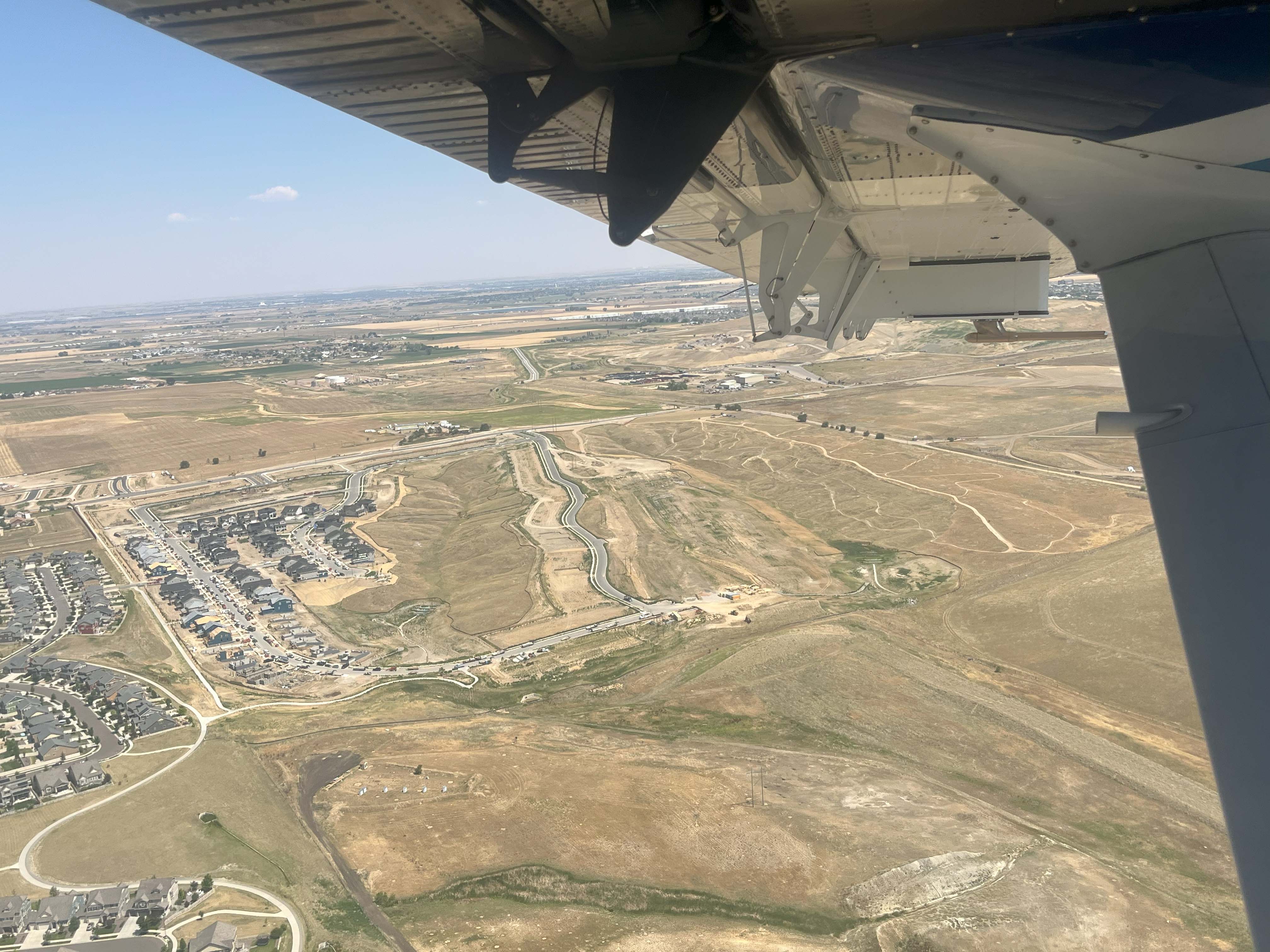 Photo taken from inside a plane of houses and fields