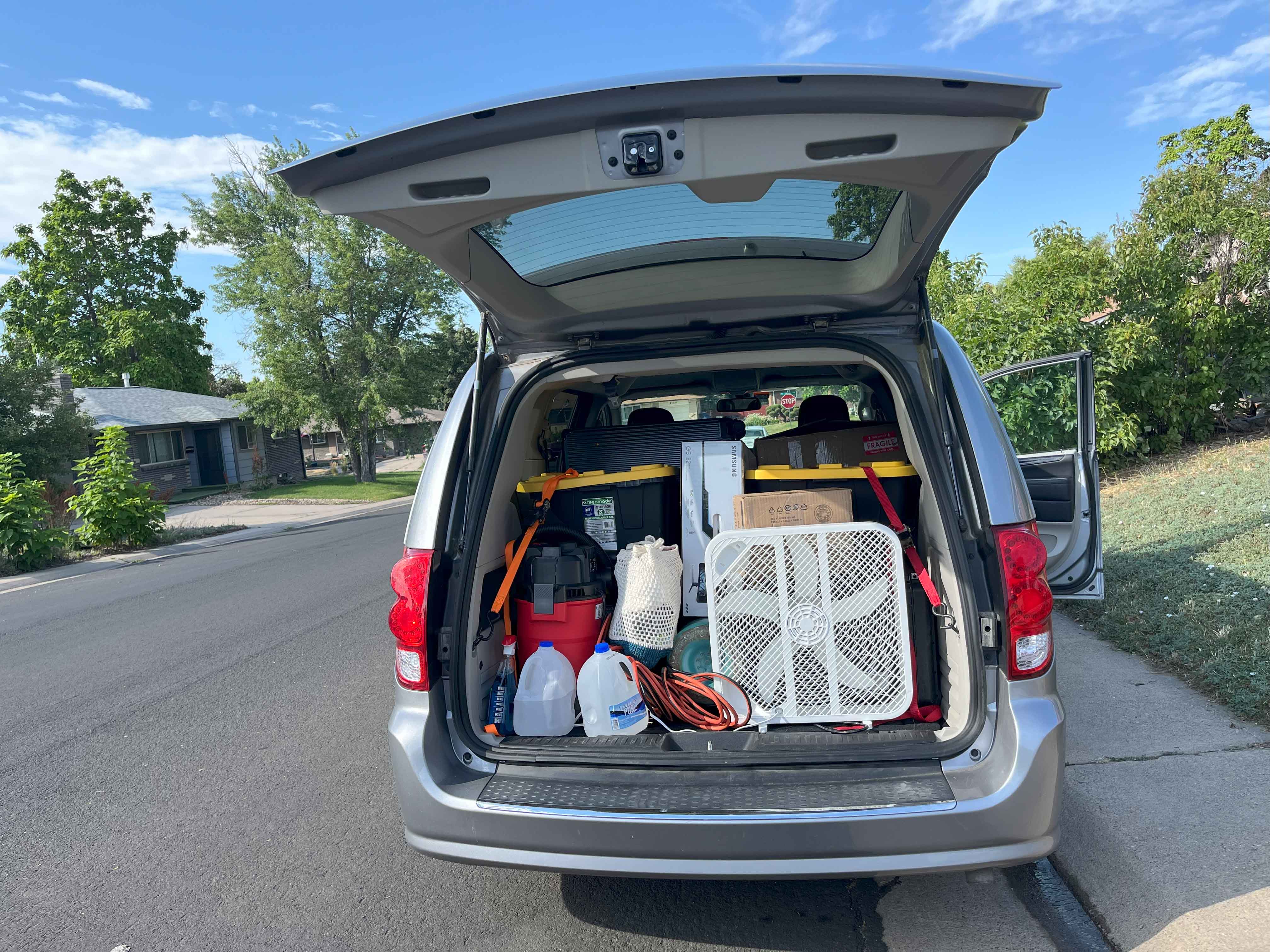 photo of the back of an SUV on the street with the trunk door open and packed with supplies and a box fan