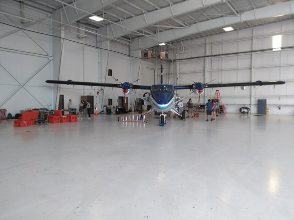 Day 5 pic small propeller plane in the corner of a large hanger