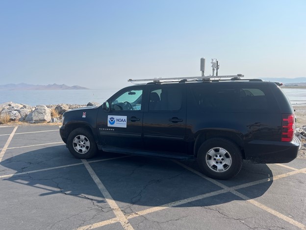 Black SUV in a parking lot facing a lake