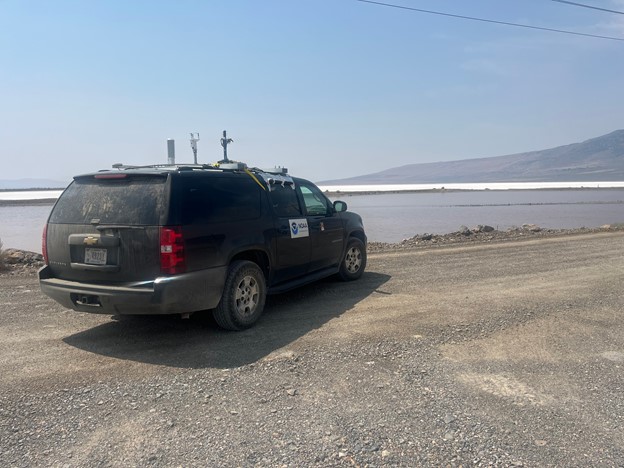 Black SUV on the side of a gravel road looking over a salt lake