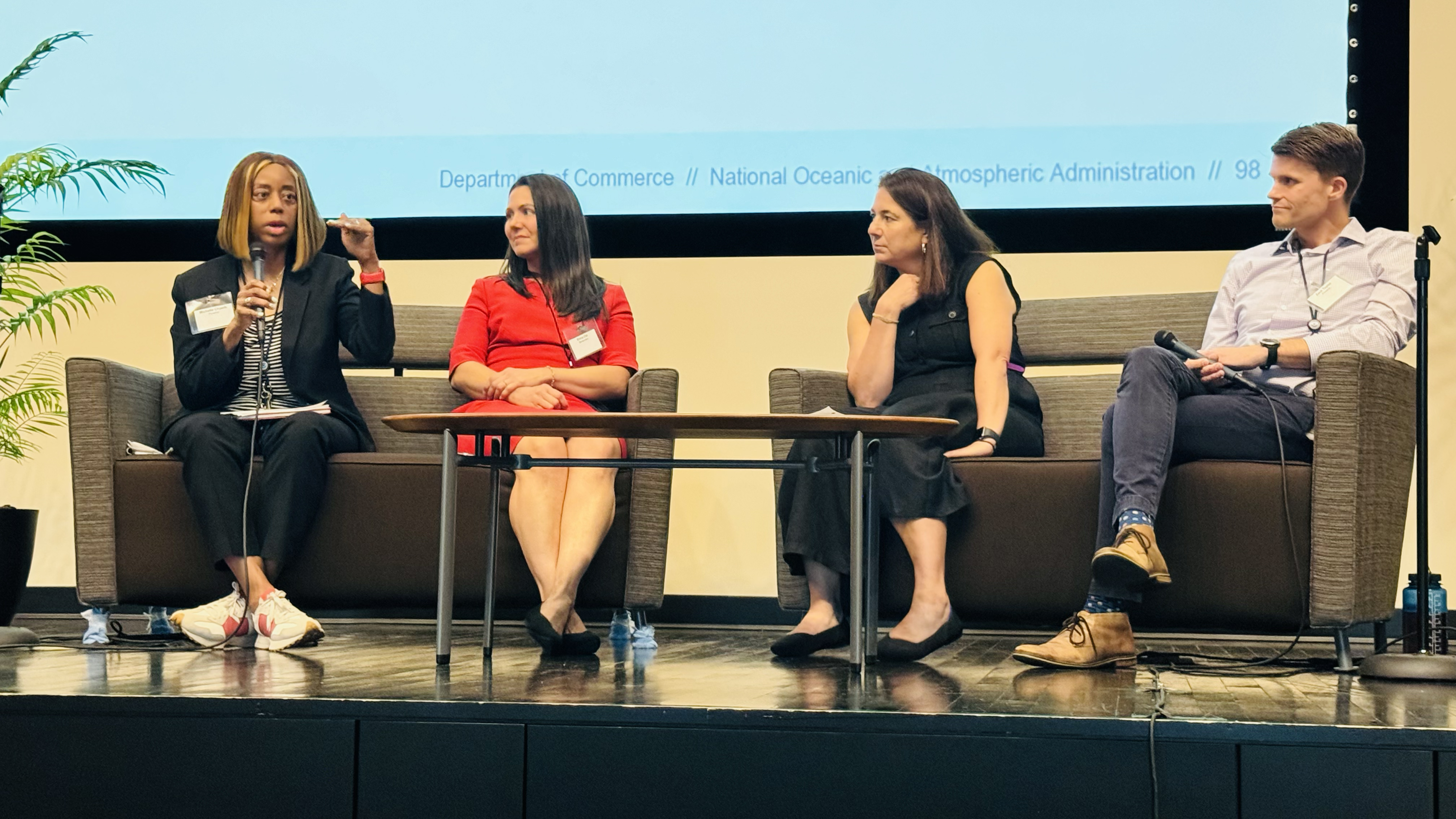 three women and one man sitting on two couches on a stage