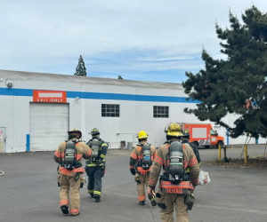 image of fire fighters in full gear walking towards a white warehouse