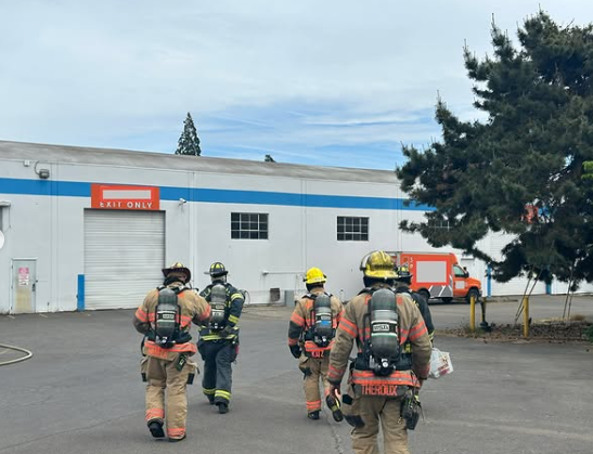 Clackamas fire image of fire fighters in full gear walking towards a white warehouse