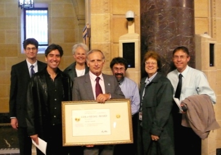 Roland Draxler holding Department of Commerce Gold Medal certificate